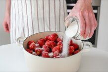 Für die Herstellung von Erdbeerkonfitüre, Gelee oder Marmelade werden werden in einem weißen Topf Erdbeeren mit Gelierzucker überstreut. | © Freepik