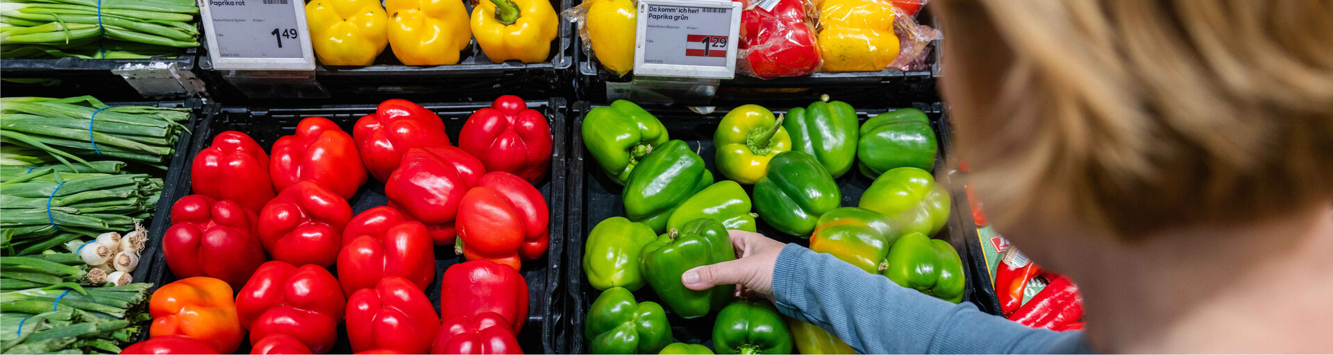 Saisonales Gemüse: Eine Frau greift nach einem grünen Paprika im Supermarkt. | © Land schafft Leben