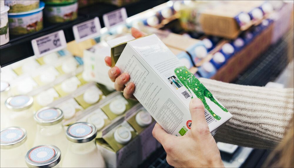 Eine Kundin hält im Supermarkt einen Liter Milch und liest die Angaben zum Nährstoffgehalt | © Land schafft Leben