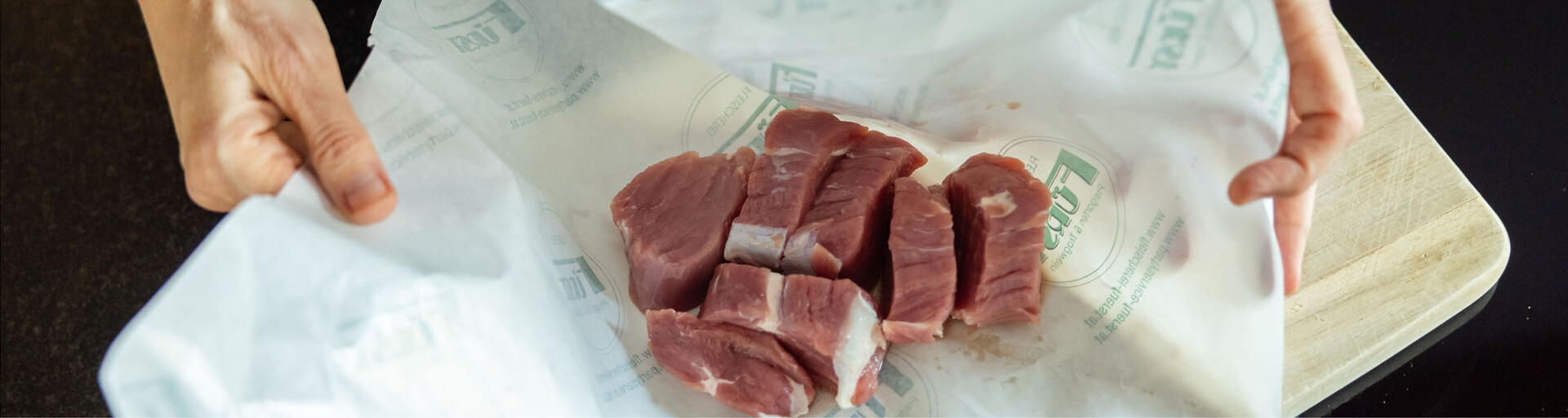 Hände packen Schweinefleisch aus | © Land schafft Leben