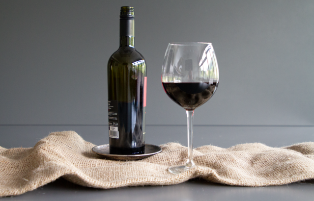 Ein Glas mit Rotwein neben einer Flasche | © Land schafft Leben