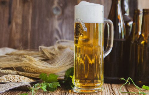 Mit Bier vollgefülltes Henkelglas auf Holztisch | © Land schafft Leben