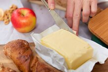 Frau bereitet eine Jause mit Butter, Weckerl Apfel und Nüssen zu | © Land schafft Leben