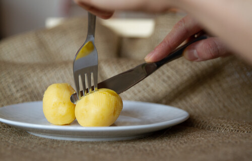 Person isst Kartoffeln mit Messer und Gabel | © Land schafft Leben