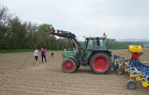 Traktor und Arbeiter stehen auf Feld | © Land schafft Leben